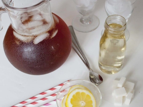 Pitcher of iced tea, bottle of simple syrup, lemon slices, and straws.