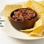 2 Ingredient Black Bean Dip in a wood bowl on a platter surrounded by tortilla chips.