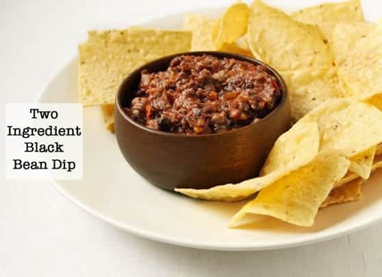 2 Ingredient Black Bean Dip in a wood bowl on a platter surrounded by tortilla chips.