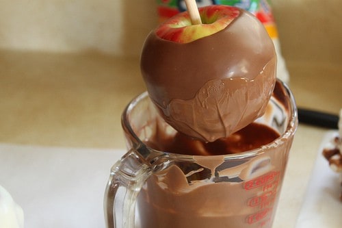 Dipping apple in melted milk chocolate.