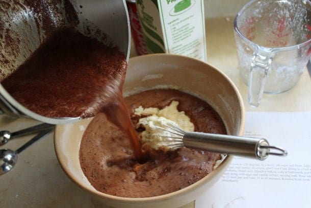 Pouring cooked syrup into gluten-free cola cake batter.