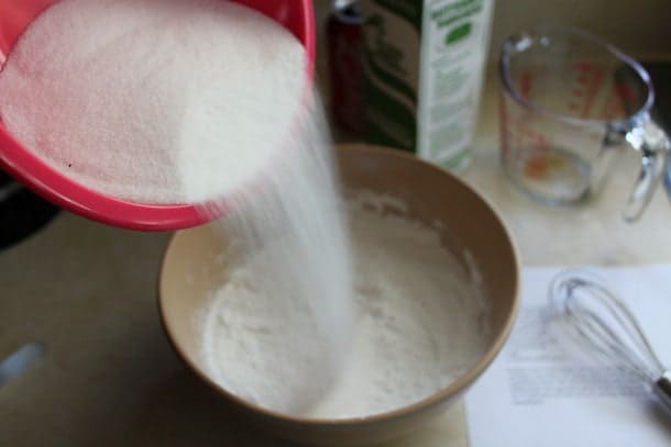 Adding sugar to gluten-free cola cake batter.