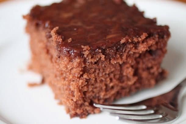 Gluten-free cola cake on white plate with fork.