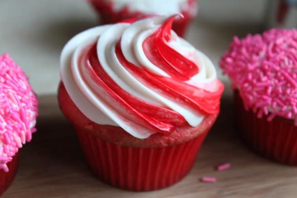 Gluten-free cupcake with red and white frosting on wood board.