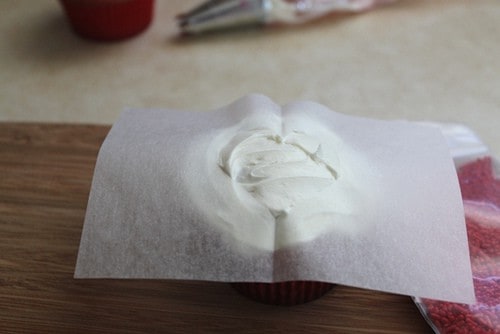 Paper heart templated on top of frosted cupcake.