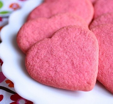 Pink gluten-free sugar cookie hearts on a plate.