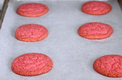 Pink gluten-free sugar cookies on a baking sheet.