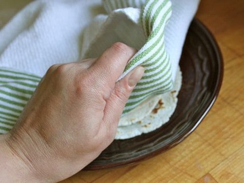 Gluten-Free Flour Tortillas on a plate being covered with a towel.