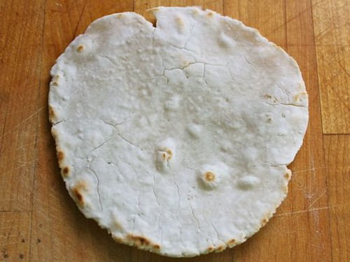 Gluten-free flour tortilla on a wooden cutting board.