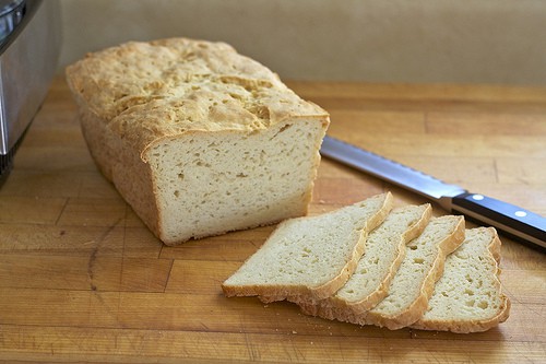 Gluten-free loaf of bread sliced on a cutting board.