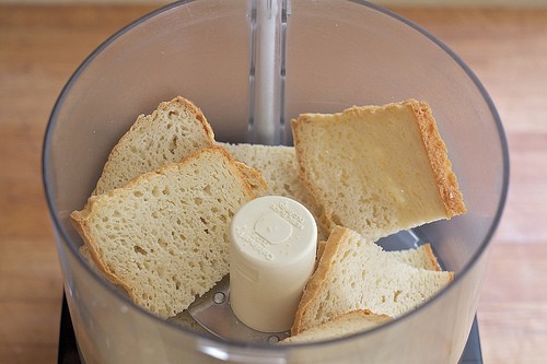 Gluten-free bread slices in the bowl of a food processor.