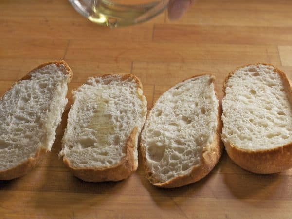 Drizzling olive oil on gluten-free bread for garlic bread.
