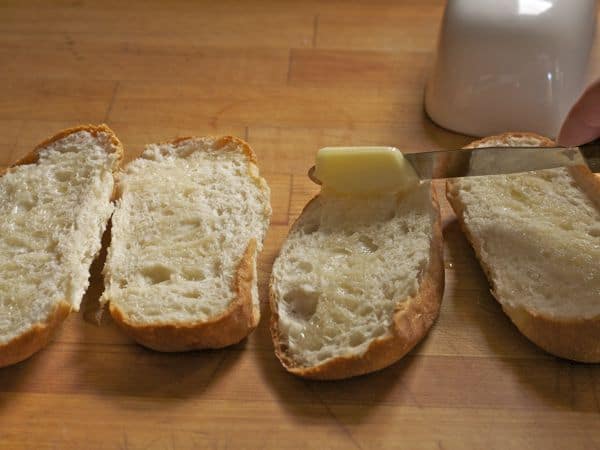 Spreading butter on gluten-free bread for garlic bread.