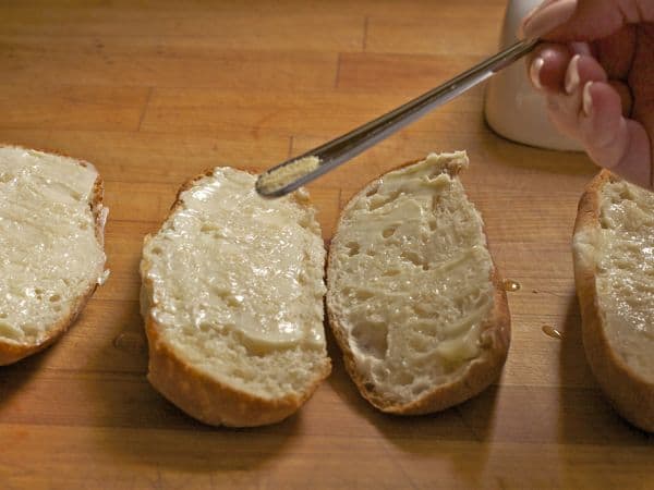 Springing garlic powder on gluten-free bread for garlic bread.