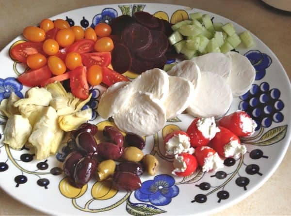 Antipasto-tallerken med ost, friske tomater, oliven, agurker og fyldte peberfrugter.