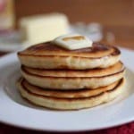 Stack of gluten-free pancakes with pat of butter and drizzle of syrup.