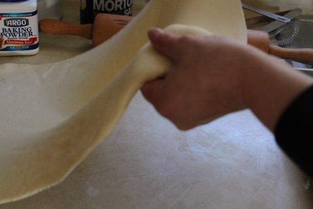 Gluten-free pizza dough being lifted off of counter.