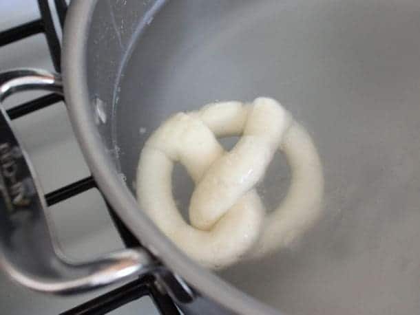 Gluten-Free Soft Pretzel floating in simmering water.