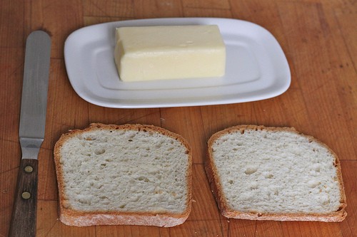 Two slices of gluten-free bread and a stick of butter.