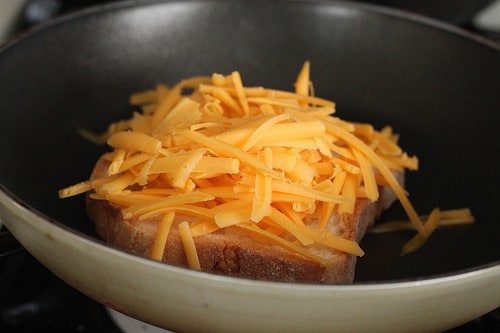 Shredded cheese on top of gluten-free bread in pan.