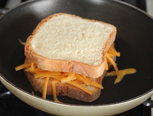 Gluten-free grilled cheese cooking in pan.