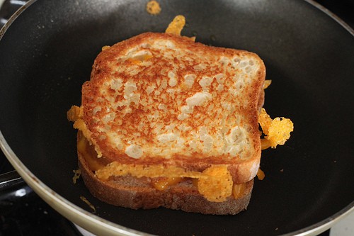 Gluten-free grilled cheese in pan. The top slice of bread is light brown and crispy.