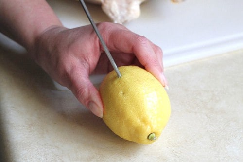 Poking holes in lemon with metal skewer.