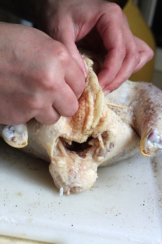 Using a wooden skewer to close chicken cavity.