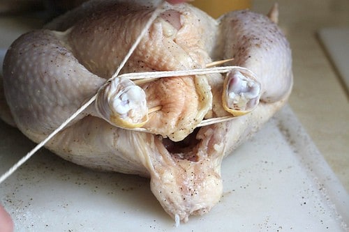 Tying chicken legs together with cooking twine.