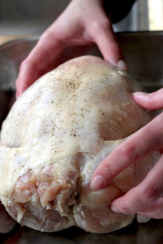 Placing a raw chicken in a roasting pan.