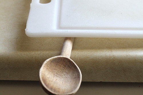 Wooden spoon under cutting board.