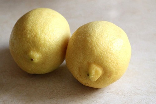 Two lemons on a cutting board.