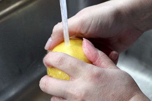 Rinsing a lemon under water.