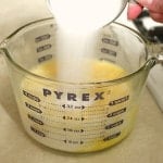 Adding sugar to the egg mixture for homemade eggnog.