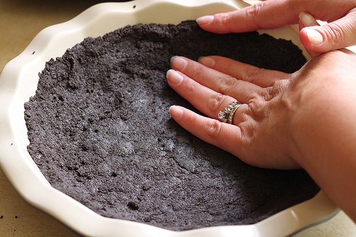 Pressing gluten-free chocolate cookie crumbs into pan.