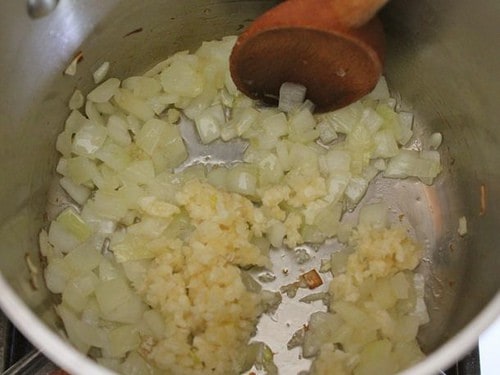 Chopped onions and minced garlic cooking in pot.