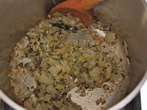 Cooked onions, garlic, and herbs cooking in a pot.