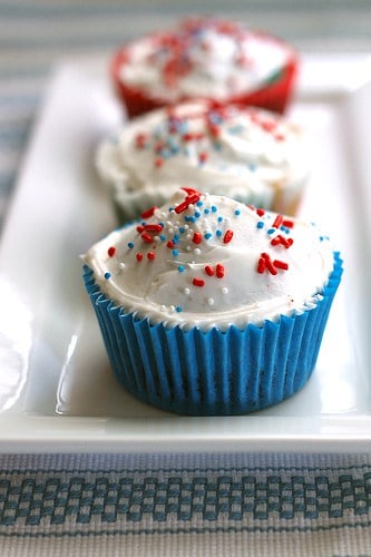 Red, White, and Blue Cupcakes frosted with vanilla frosting on white platter.