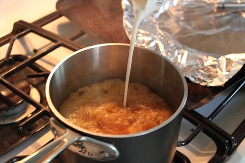 Pouring cream into caramel sauce.