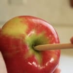 Placing wooden stick in center of apple.