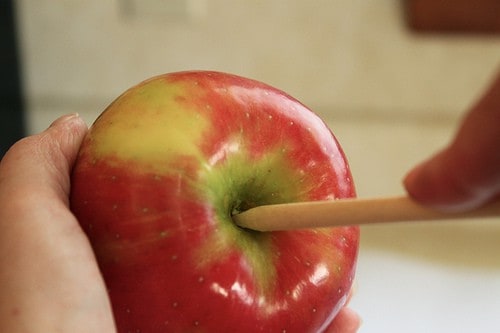 Placing wooden stick in center of apple.