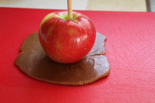 Red apple sits on top of rolled out caramel.