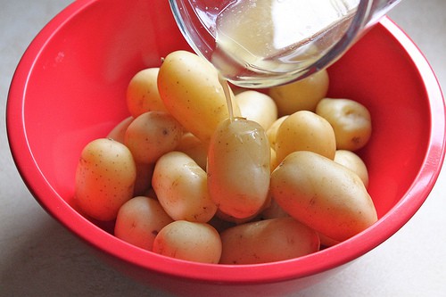 Pouring melted butter on steamed potatoes.