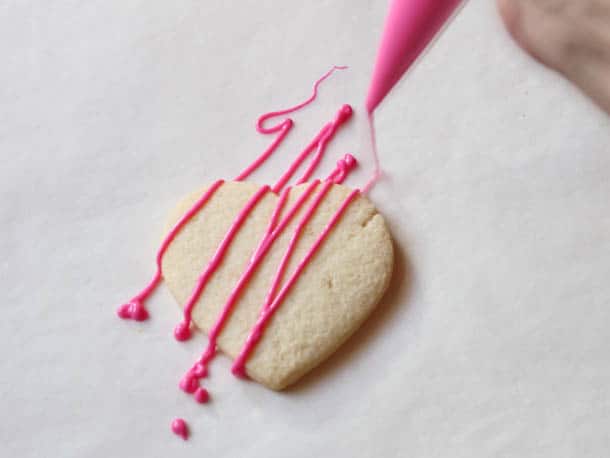 Drizzling pink chocolate over a baked gluten-free sugar cookie.
