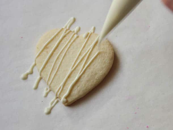 Drizzling a gluten-free cookie with white melted chocolate.