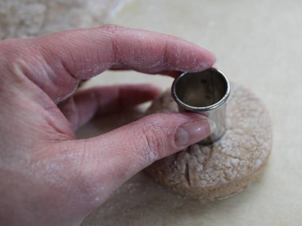 Gluten-free apple cider doughnut being cut with a cutter.