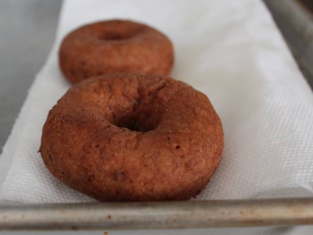 Gluten-Free Vegan Apple Cider Doughnuts on a baking sheet with a paper towel.