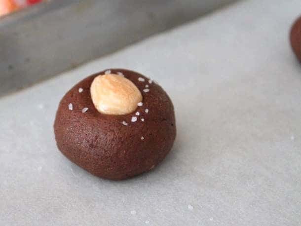 Gluten-Free Chocolate Almond Cookie dough on a baking sheet. Topped with almond and kosher salt.