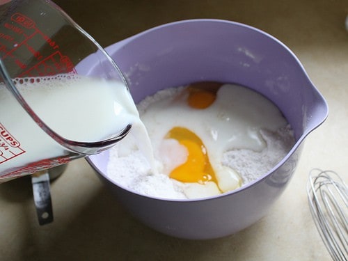 Adding milk to gluten-free chocolate chip pancake batter.