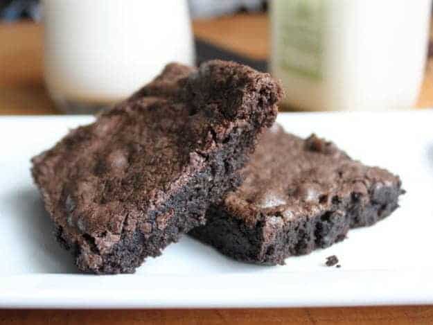 Two gluten-free brownies on a white platter.